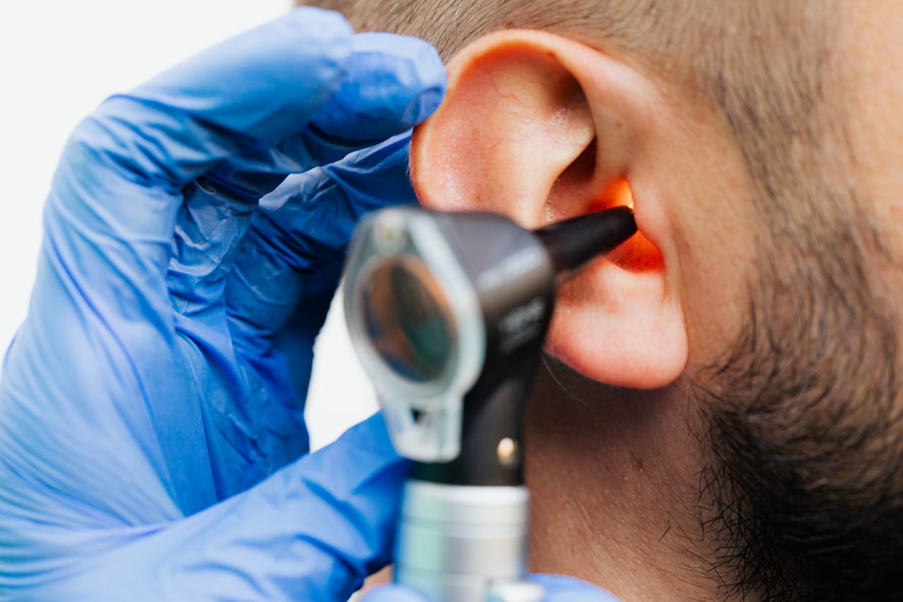 who-we-are Close-up of a doctor using an otoscope to examine a patient's ear in a clinical setting.